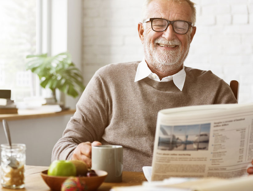 old man having tea and reading the newspaper