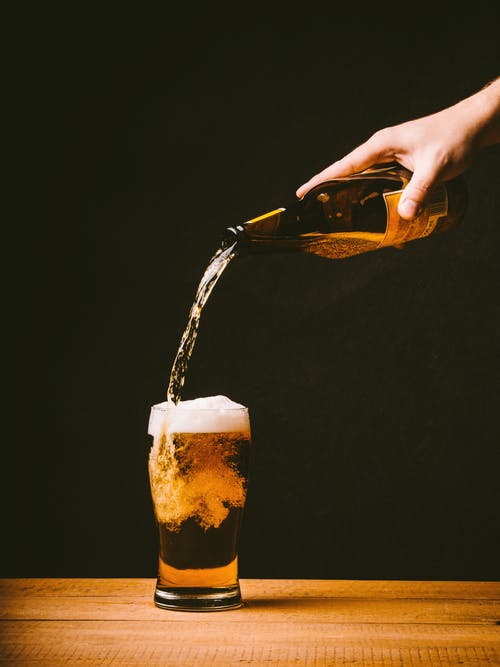 pouring beer on a pint glass