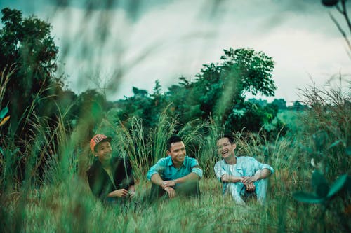 three men laughing on the grass