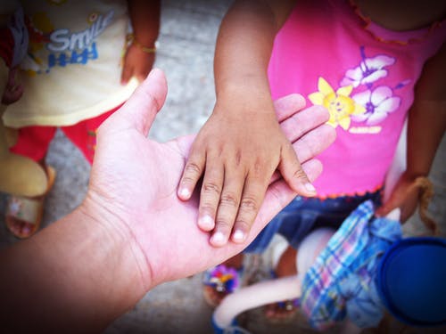 child putting her hand on dad hand