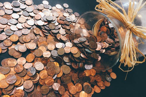 glass jar pouring coins on table